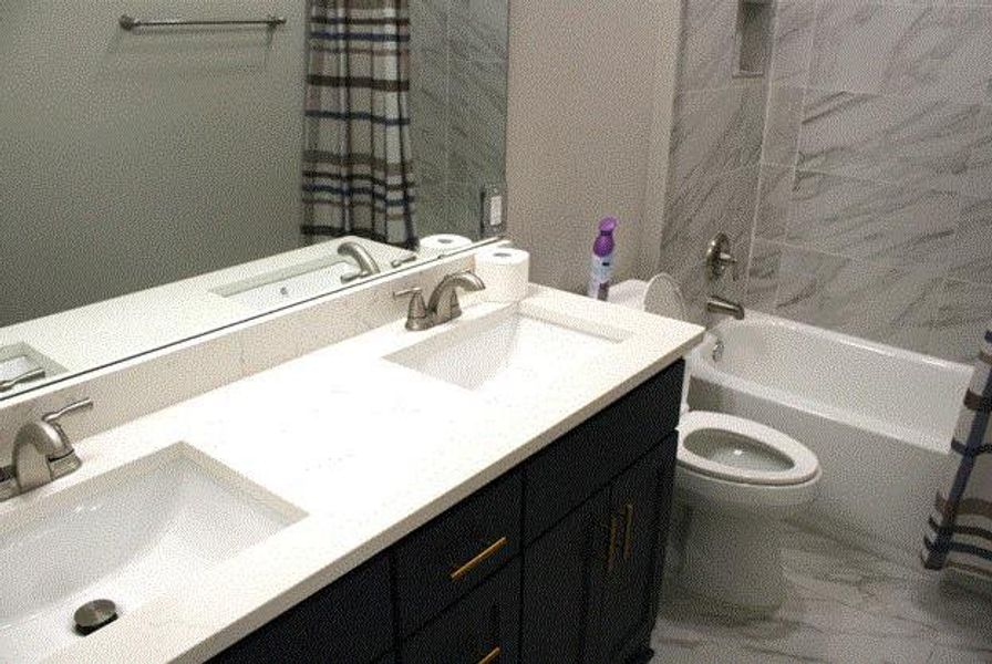 Full bathroom featuring shower / bathtub combination with curtain and double vanity