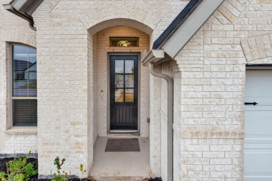 Charming entrance with a covered porch, brick exterior, and a stylish black front door with glass panels, providing a welcoming first impression. Charming entrance with a covered porch, brick exterior, and a stylish black front door with glass panels, providing a welcoming first impression.