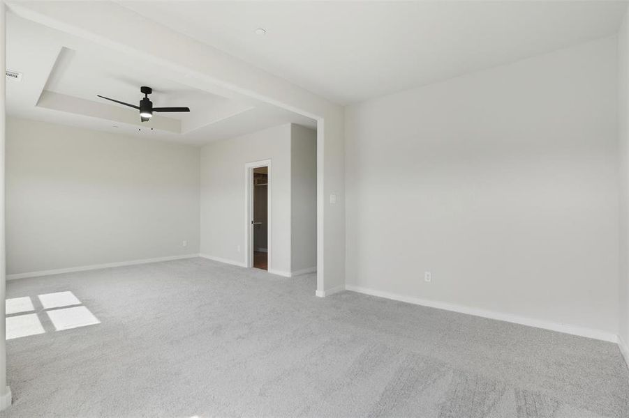Spare room featuring carpet floors, a raised ceiling, and a ceiling fan Spare room featuring carpet floors, a raised ceiling, and a ceiling fan