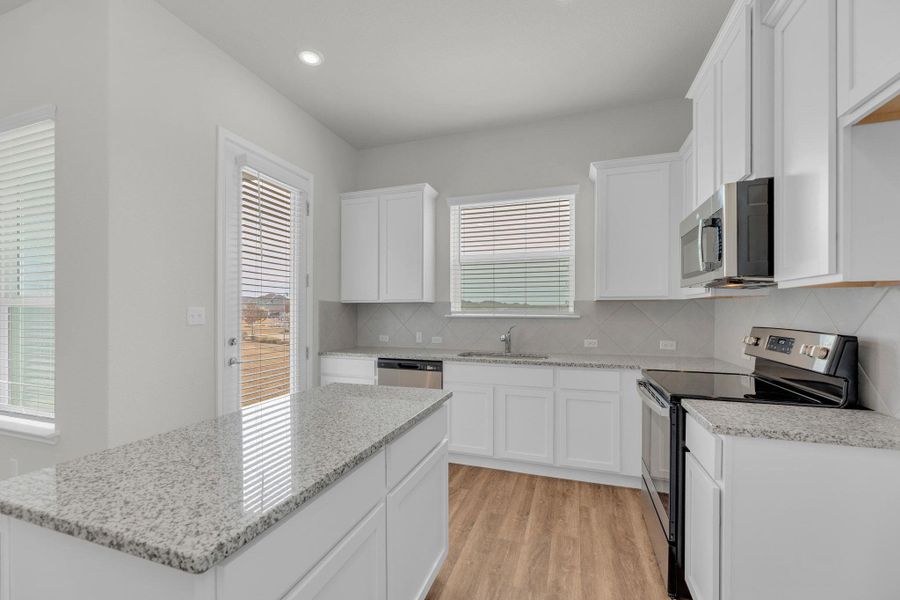 Kitchen with stainless steel appliances, white cabinetry, light wood-style flooring, a kitchen island, and recessed lighting