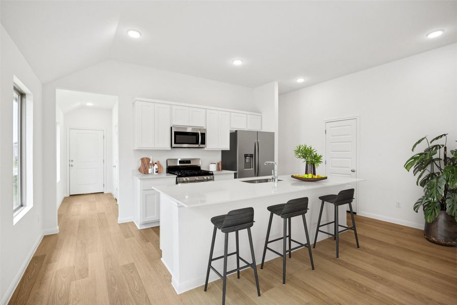 Kitchen with white cabinets, a kitchen bar, light wood-type flooring, stainless steel appliances, and a center island with sink Kitchen with white cabinets, a kitchen bar, light wood-type flooring, stainless steel appliances, and a center island with sink