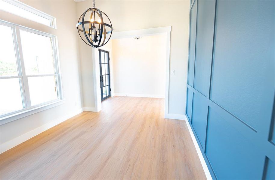 Unfurnished dining area with a chandelier and light wood-style floors