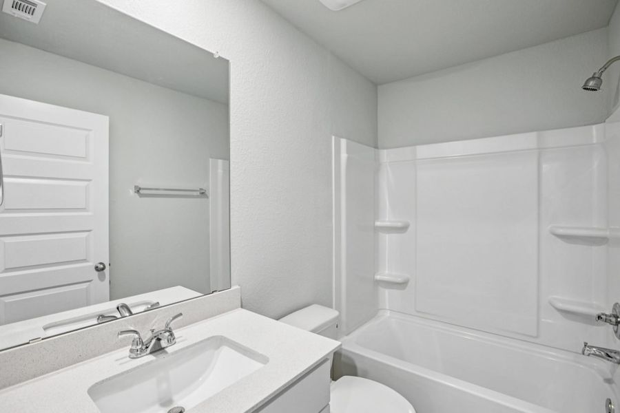 Image of a bathroom with light grey walls, a white vanity, a large mirror, and a white shower with a tub Image of a bathroom with light grey walls, a white vanity, a large mirror, and a white shower with a tub