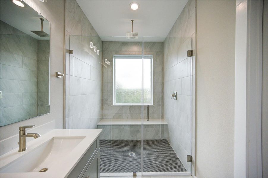 Large oversized shower with rain shower head and shower bench.