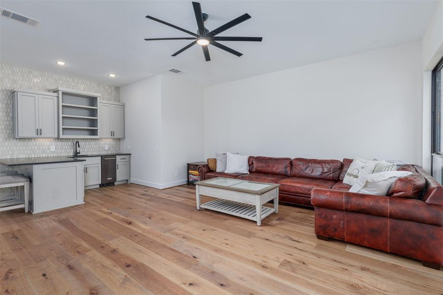 The geometric fully tiled accent wall adds a touch of elegance to this spacious multipurpose room, with built in wet bar and Kitchen Aid ice maker.  A decorative granite surface bar with overhang for casual seating is a good size for serving chilled drinks and snacks for all your guests to savor.