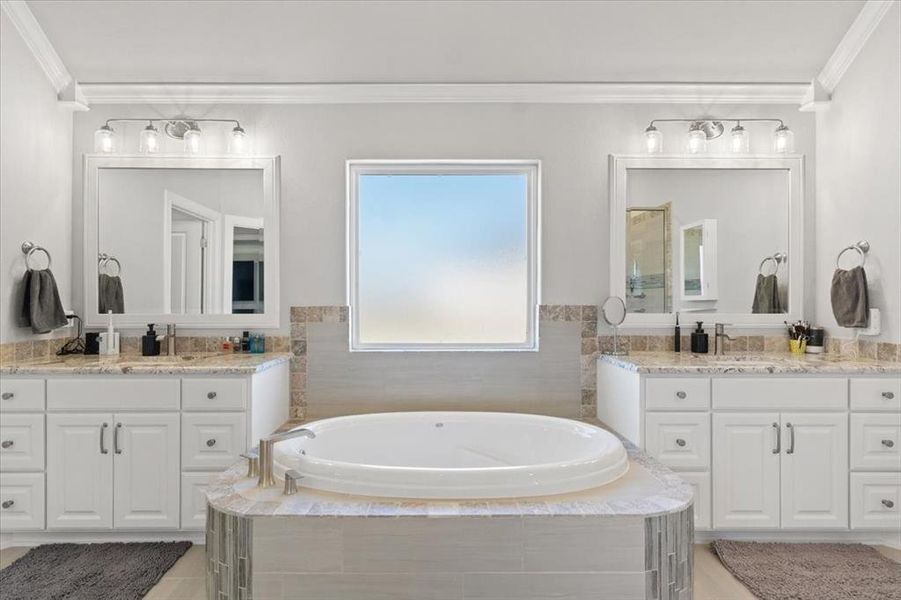 Full bathroom with two vanities, crown molding, and a bath