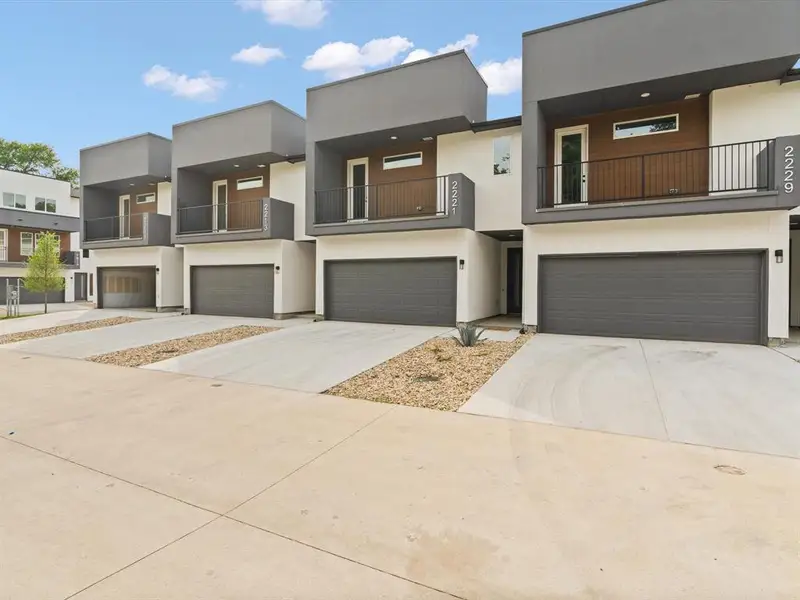 View of front of property featuring a garage, stucco siding, concrete driveway, and a balcony View of front of property featuring a garage, stucco siding, concrete driveway, and a balcony