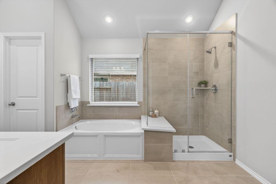 This modern bathroom features a spacious shower with glass doors, a cozy bathtub, and sleek tile flooring. The room is well-lit with recessed lighting, and a large window provides natural light. This modern bathroom features a spacious shower with glass doors, a cozy bathtub, and sleek tile flooring. The room is well-lit with recessed lighting, and a large window provides natural light.