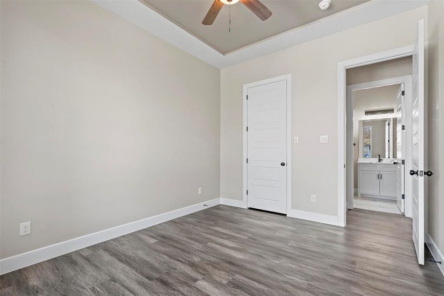 Unfurnished bedroom featuring sink, light wood-type flooring, and a raised ceiling