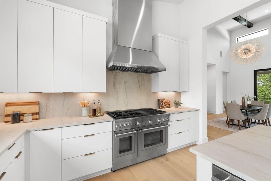 Culinary excellence awaits in this well-appointed kitchen, featuring a professional-grade range and pristine countertops, flowing into a bright dining area.