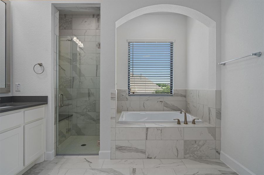 Soaking tub set within a tiled alcove featuring an arched entry