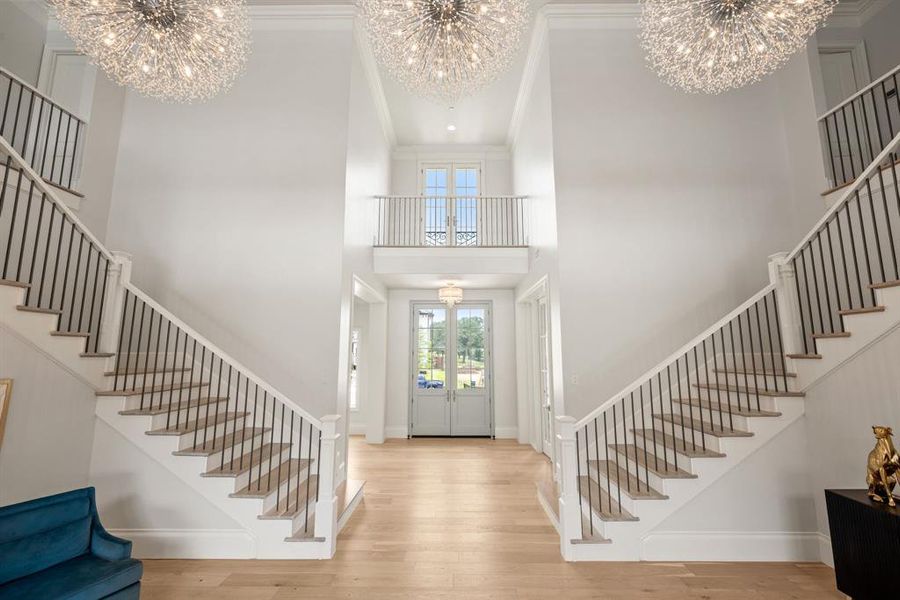 Entryway with a chandelier, stairs, a towering ceiling, wood finished floors, and crown molding Entryway with a chandelier, stairs, a towering ceiling, wood finished floors, and crown molding