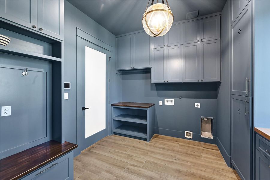 Mud/Laundry room featuring custom lighting and butcher block countertops.