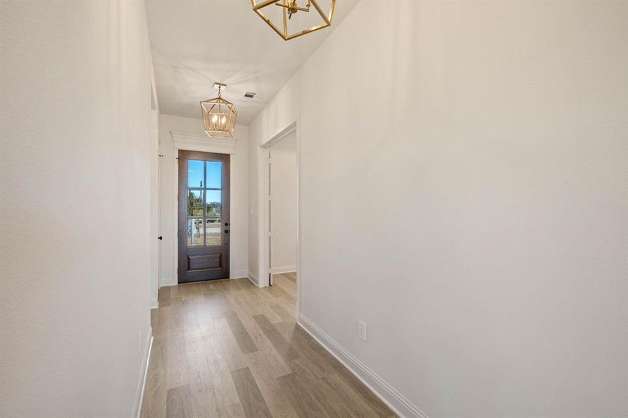 Entryway featuring a chandelier, light wood-type flooring, and baseboards