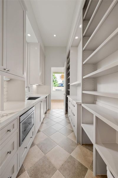 The scullery area behind the kitchen offers a secondary sink, Thermador dishwasher and microwave.
