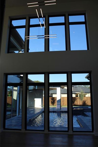 Doorway to outside with hardwood / wood-style floors, a towering ceiling, and a healthy amount of sunlight