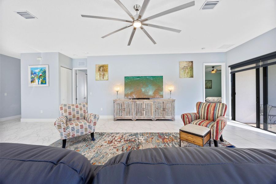 Living area featuring a ceiling fan and light marble finish flooring