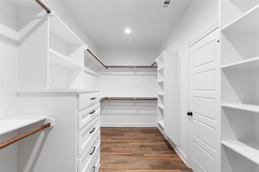Spacious closet featuring dark wood-style flooring and visible vents