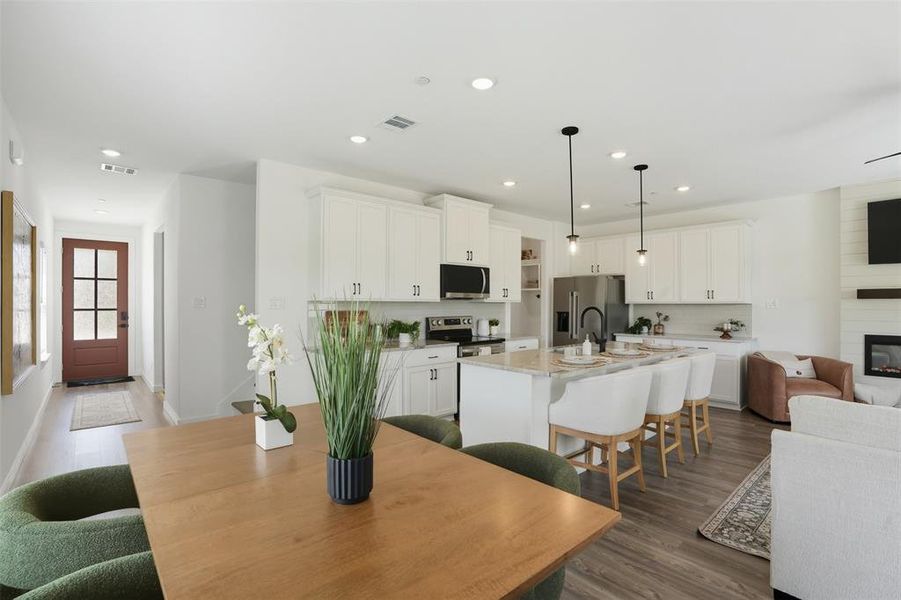 Dining room featuring dark wood-style flooring, recessed lighting, and a large fireplace Dining room featuring dark wood-style flooring, recessed lighting, and a large fireplace