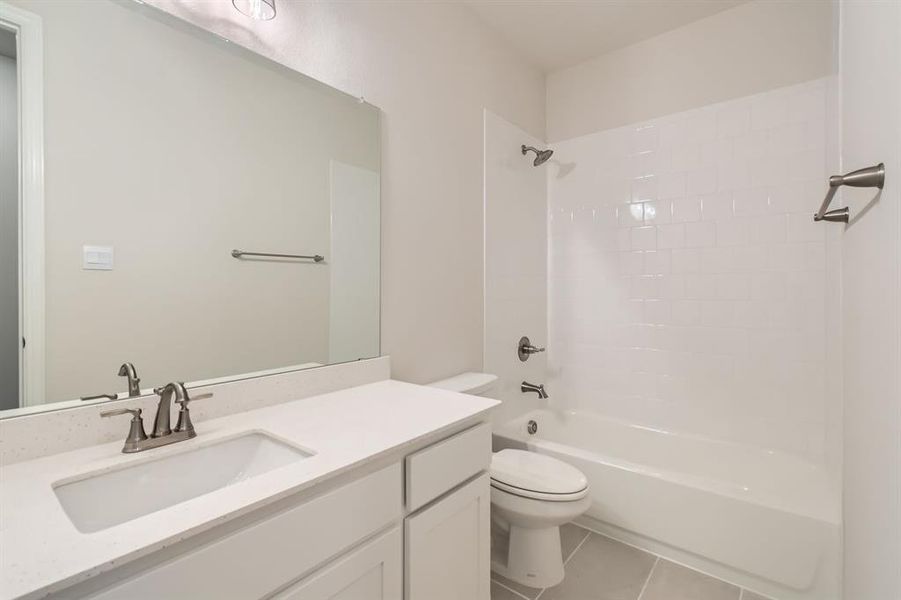 Full bathroom featuring toilet, vanity, tile patterned floors, and shower / washtub combination