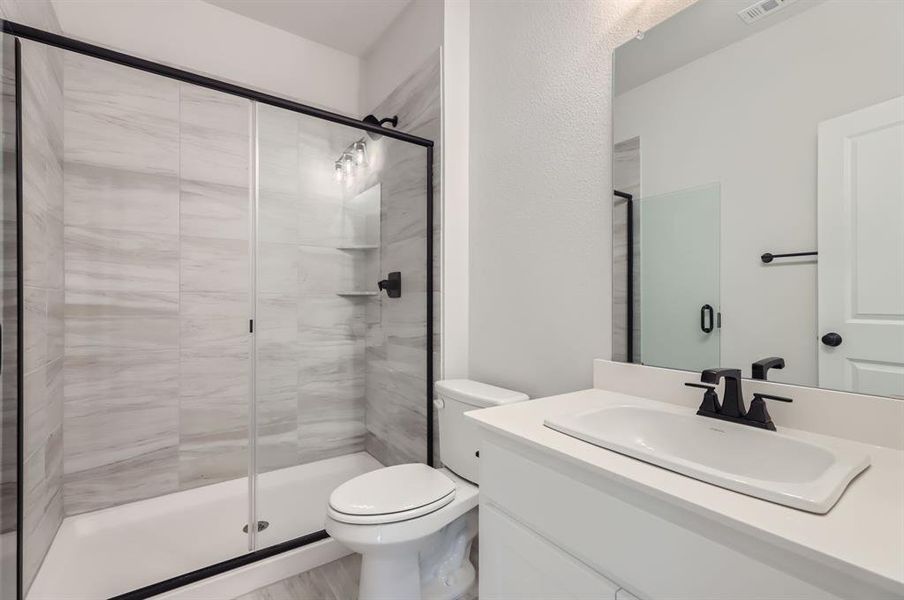 Bathroom with vanity, toilet, and a shower with door