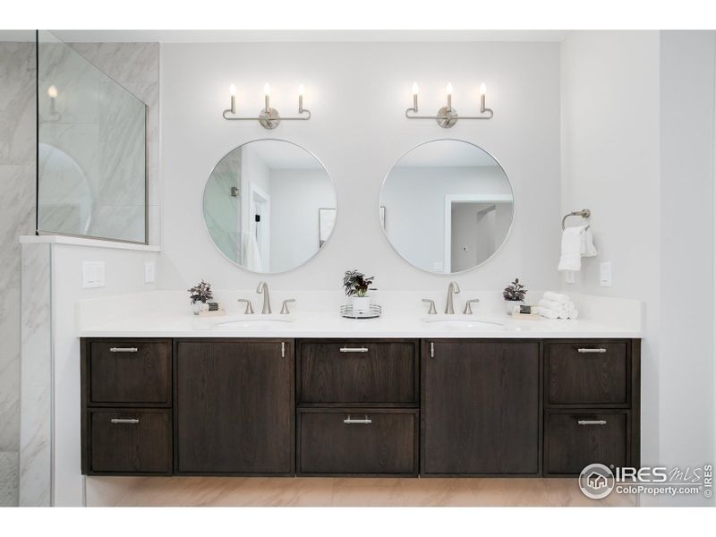 Primary bathroom with double vanity, linen closet, quartz counter, and luxury walk-in shower with penny accent tiling.