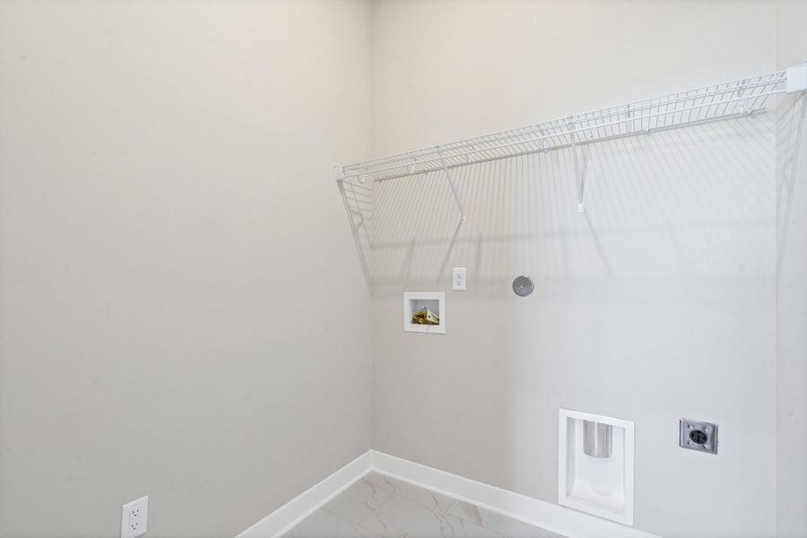 Utility space featuring a wire shelving unit, appliance hookups, and light-toned flooring