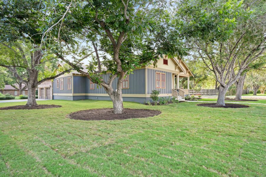 A welcoming front porch extends from a home with blue siding, set amidst mature trees and a manicured lawn. A welcoming front porch extends from a home with blue siding, set amidst mature trees and a manicured lawn.
