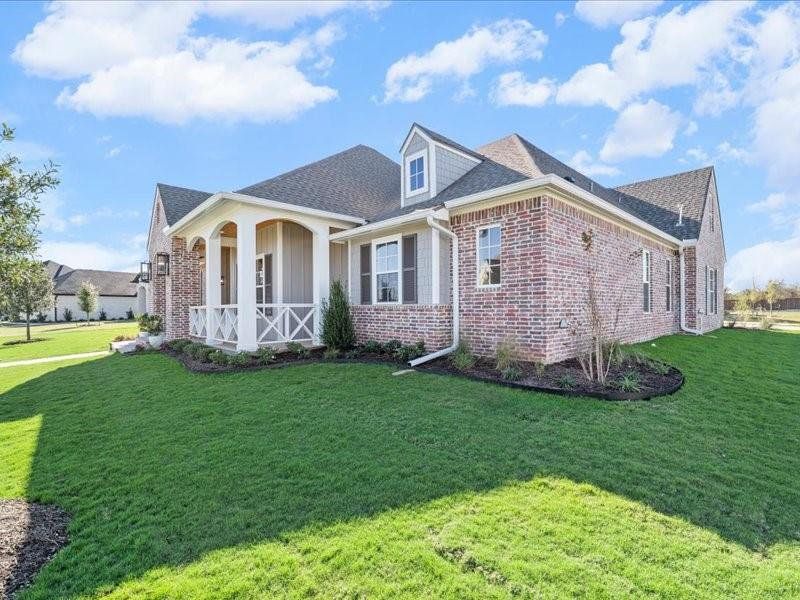 View of front of house featuring a front lawn, brick siding, a porch, and roof with shingles