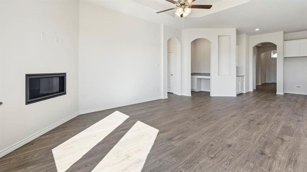 Spacious living area featuring light-colored flooring, a modern fireplace, and arched doorways Spacious living area featuring light-colored flooring, a modern fireplace, and arched doorways