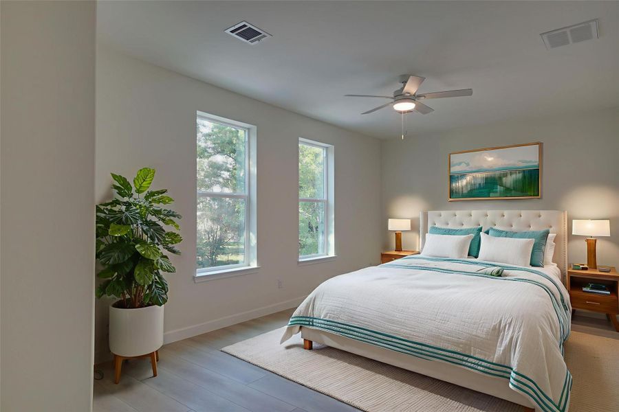 Serene primary bedroom with wide-plank floors,neutral palette, and two tall windows filling theroom with natural light. Spacious layout fits a kingbed, with ceiling fan and space for nightstands or aseating area. Serene primary bedroom with wide-plank floors,neutral palette, and two tall windows filling theroom with natural light. Spacious layout fits a kingbed, with ceiling fan and space for nightstands or aseating area.