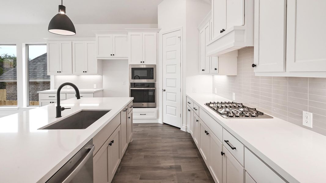 Kitchen featuring appliances with stainless steel finishes, a sink, light countertops, decorative backsplash, and white cabinets