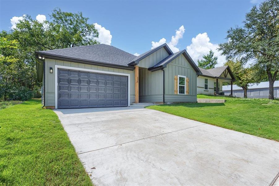 View of front of house with board and batten siding, driveway, roof with shingles, a front yard, and an attached garage View of front of house with board and batten siding, driveway, roof with shingles, a front yard, and an attached garage