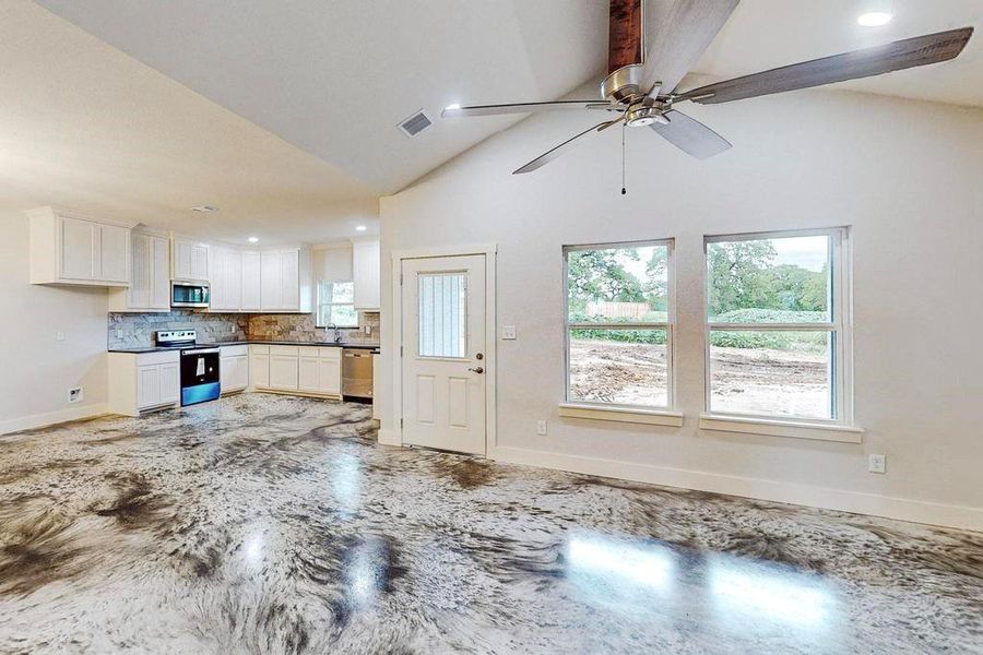 Unfurnished living room with high vaulted ceiling, ceiling fan, and sink