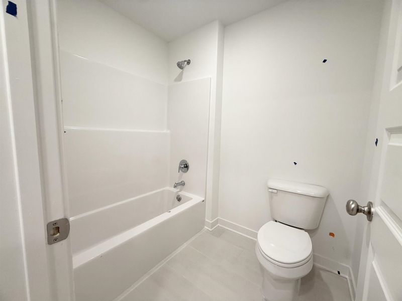 Bathroom featuring toilet, baseboards, shower / bathtub combination, and tile patterned floors Bathroom featuring toilet, baseboards, shower / bathtub combination, and tile patterned floors