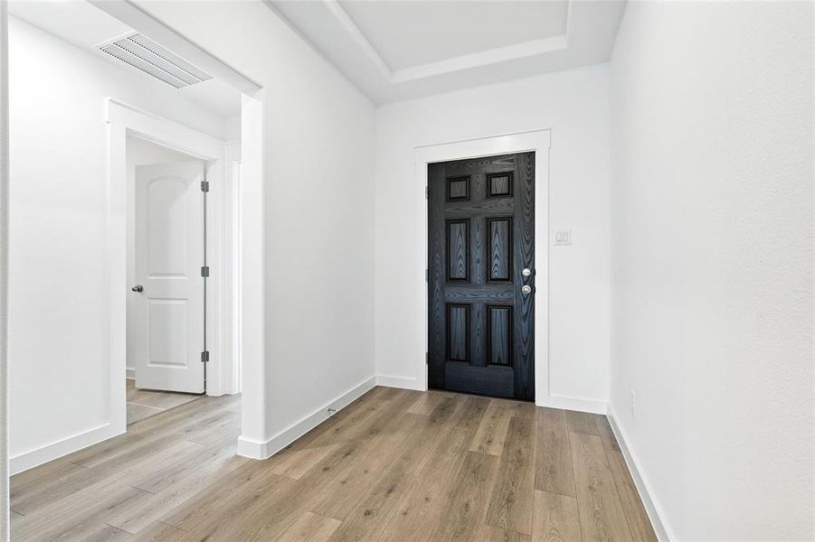 Entryway featuring light wood-type flooring and a tray ceiling