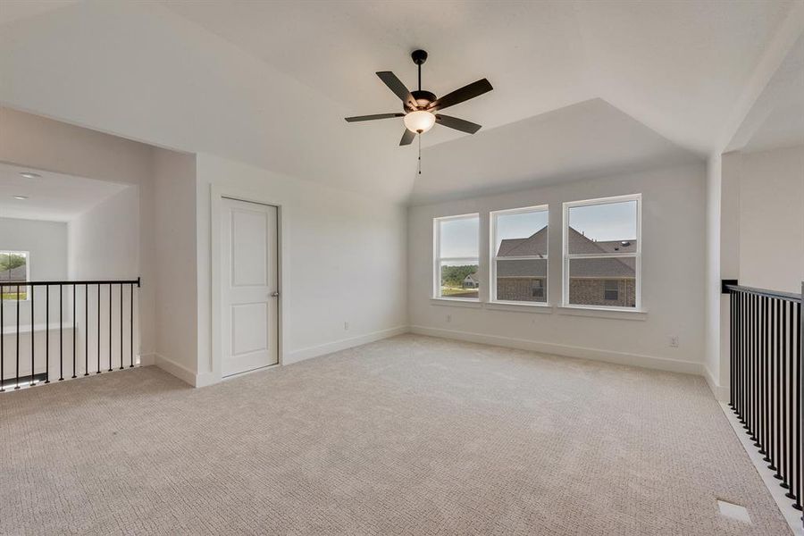 Unfurnished bedroom with vaulted ceiling, light carpet, and ceiling fan Unfurnished bedroom with vaulted ceiling, light carpet, and ceiling fan