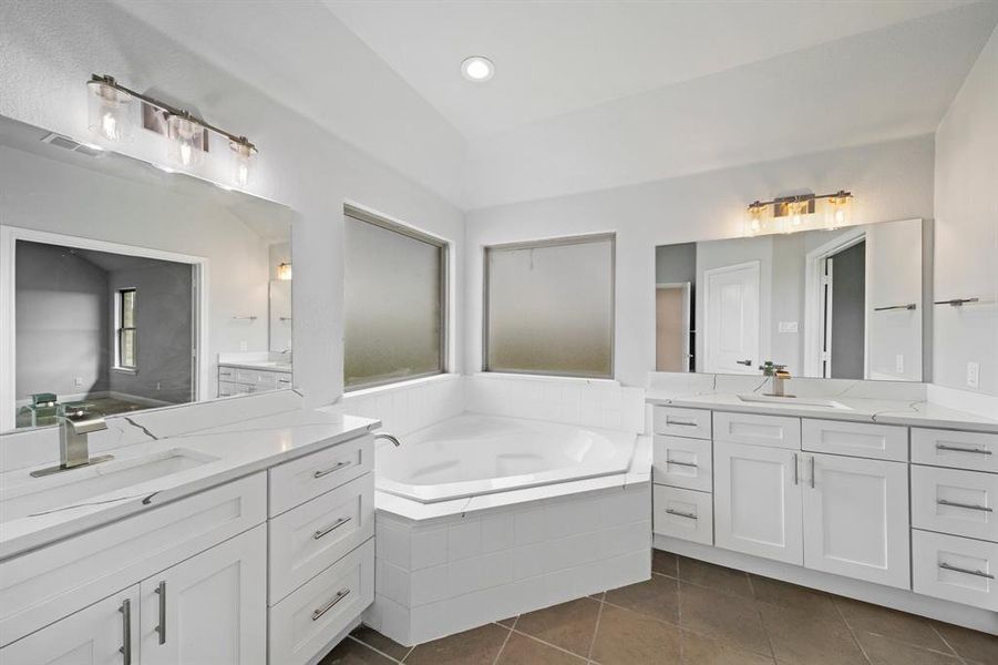 Bathroom with tiled tub, tile patterned flooring, and dual bowl vanity