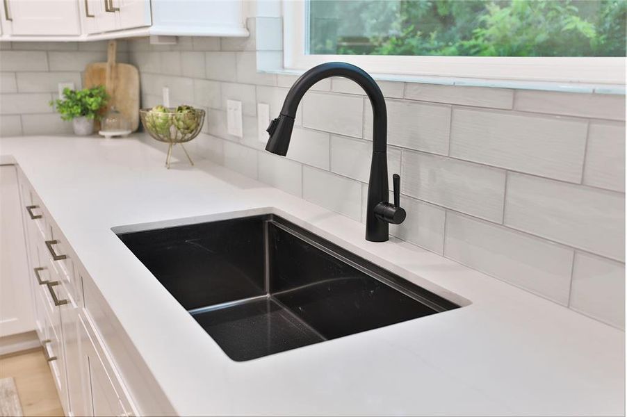 Sleek black stainless under-mount sink set against a backdrop of frosty 3x9 subway tiles, offering a timeless and chic kitchen aesthetic.