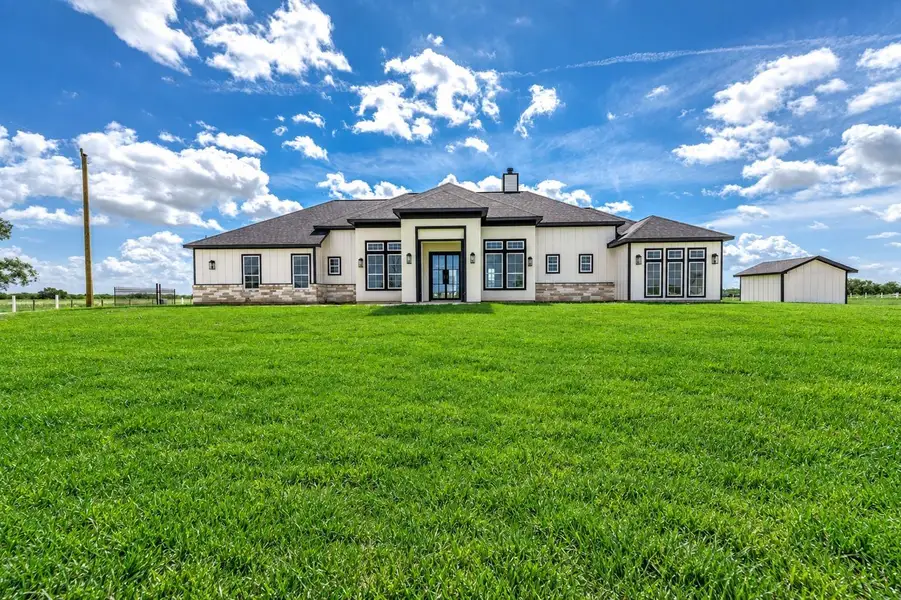 Beautiful custom home with a modern exterior, stone accents, and plenty of open green space surrounding the property. Beautiful custom home with a modern exterior, stone accents, and plenty of open green space surrounding the property.