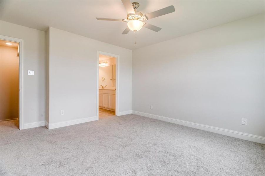 Unfurnished bedroom with light colored carpet, a ceiling fan, and ensuite bathroom