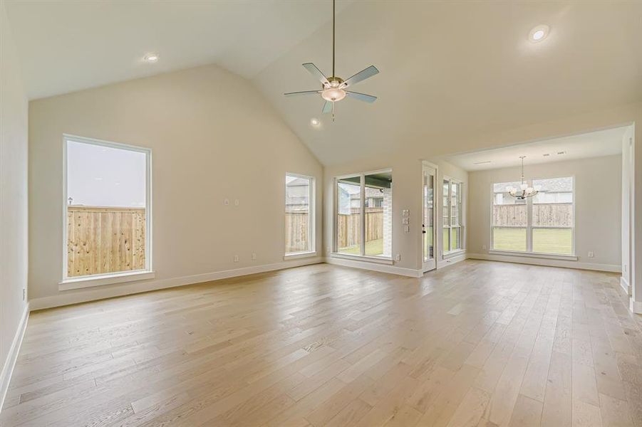 Unfurnished living room with light wood finished floors, high vaulted ceiling, a chandelier, ceiling fan, and recessed lighting
