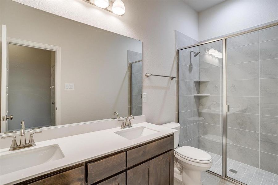 Bathroom featuring vanity, toilet, an enclosed shower, and tile patterned floors