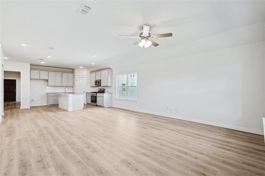 Unfurnished living room with sink, ceiling fan, and light hardwood / wood-style floors