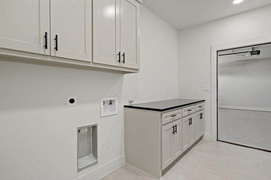 Laundry area with washer hookup, electric dryer hookup, light colored carpet, and cabinets