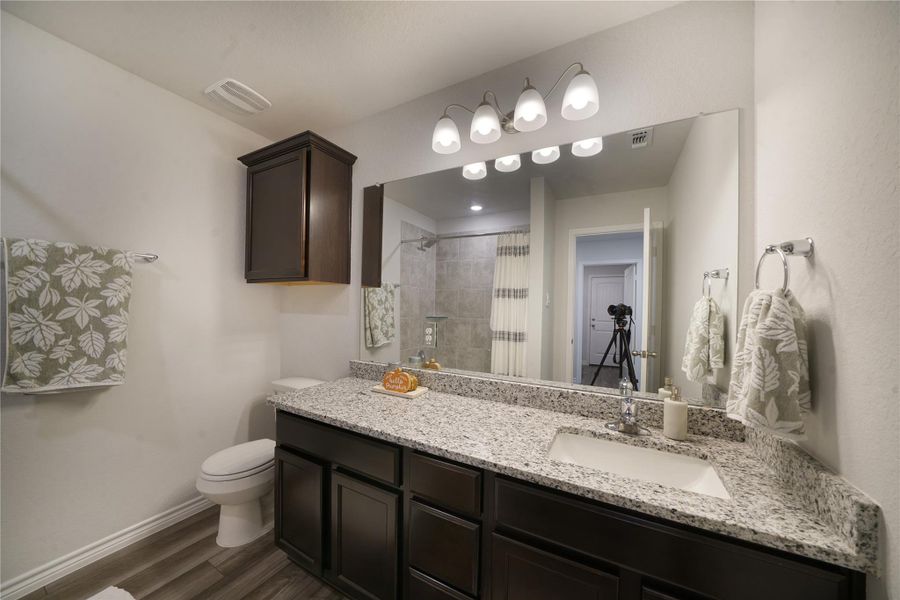 Bathroom featuring vanity, dark wood finished floors, and a tile shower