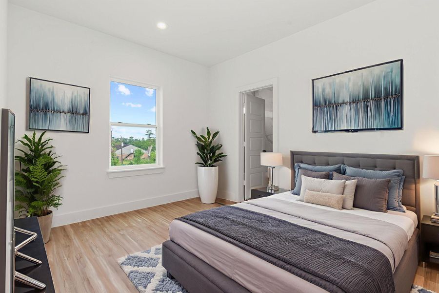 This inviting secondary bedroom features sleek laminate flooring, recessed lighting, and a bright window that fills the space with natural light—perfectly staged to showcase its potential.
