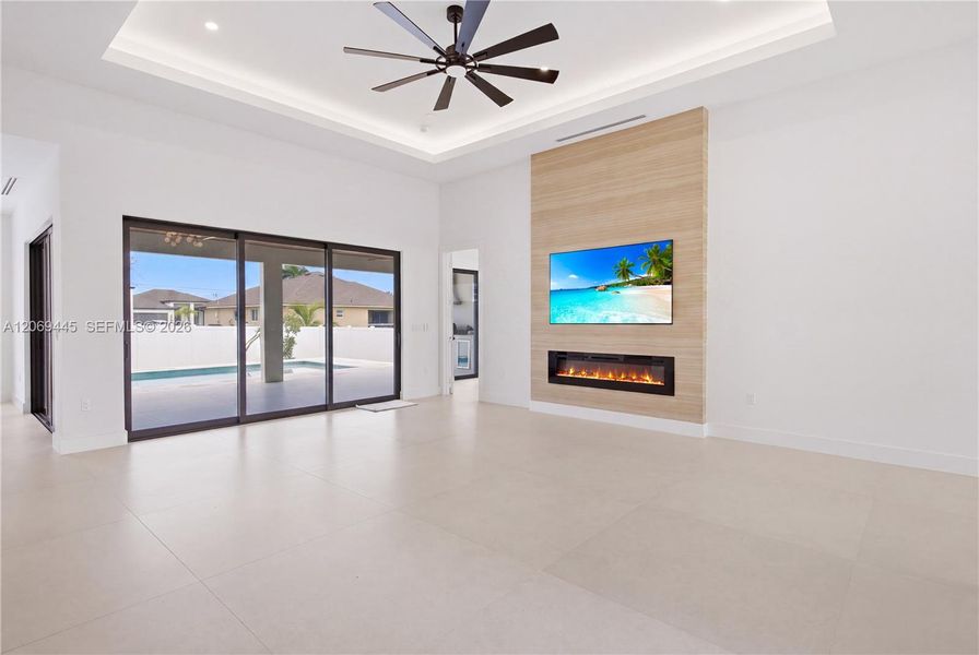 Spacious open-concept living room with soaring tray ceilings and modern recessed lighting. Spacious open-concept living room with soaring tray ceilings and modern recessed lighting.