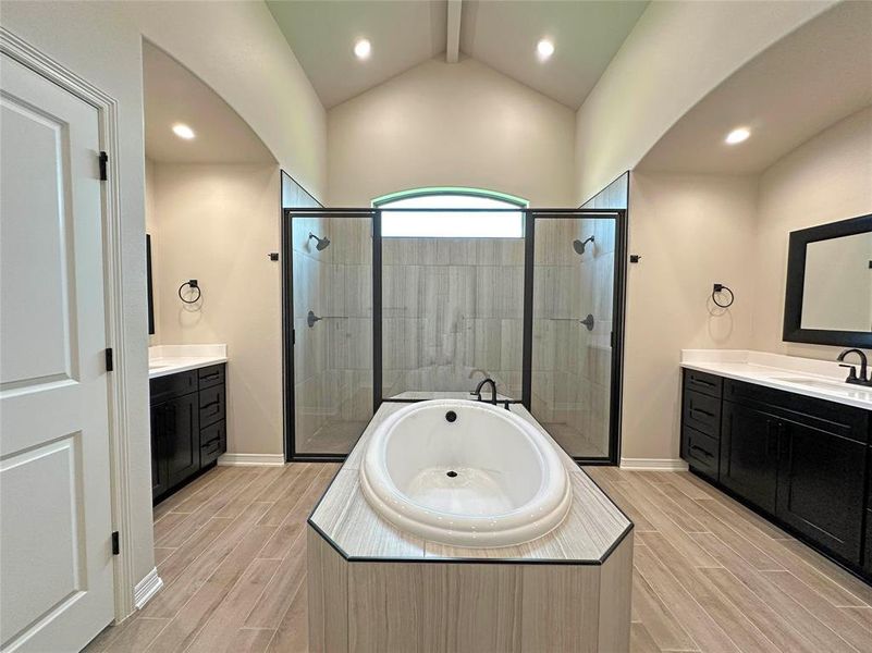 Bathroom featuring a shower stall, recessed lighting, two vanities, wood tiled floors, and a bath