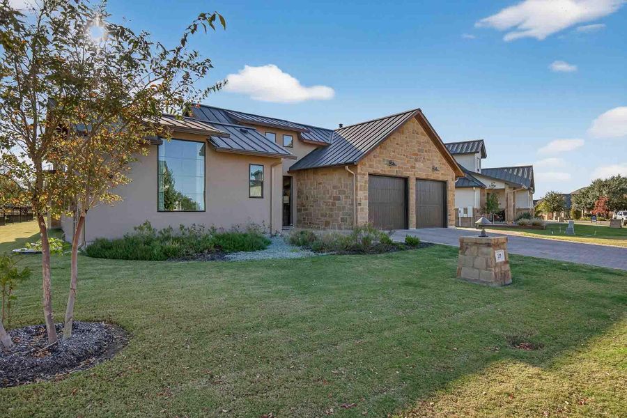 View of front facade with a standing seam roof, a metal roof, a front lawn, driveway, and a garage